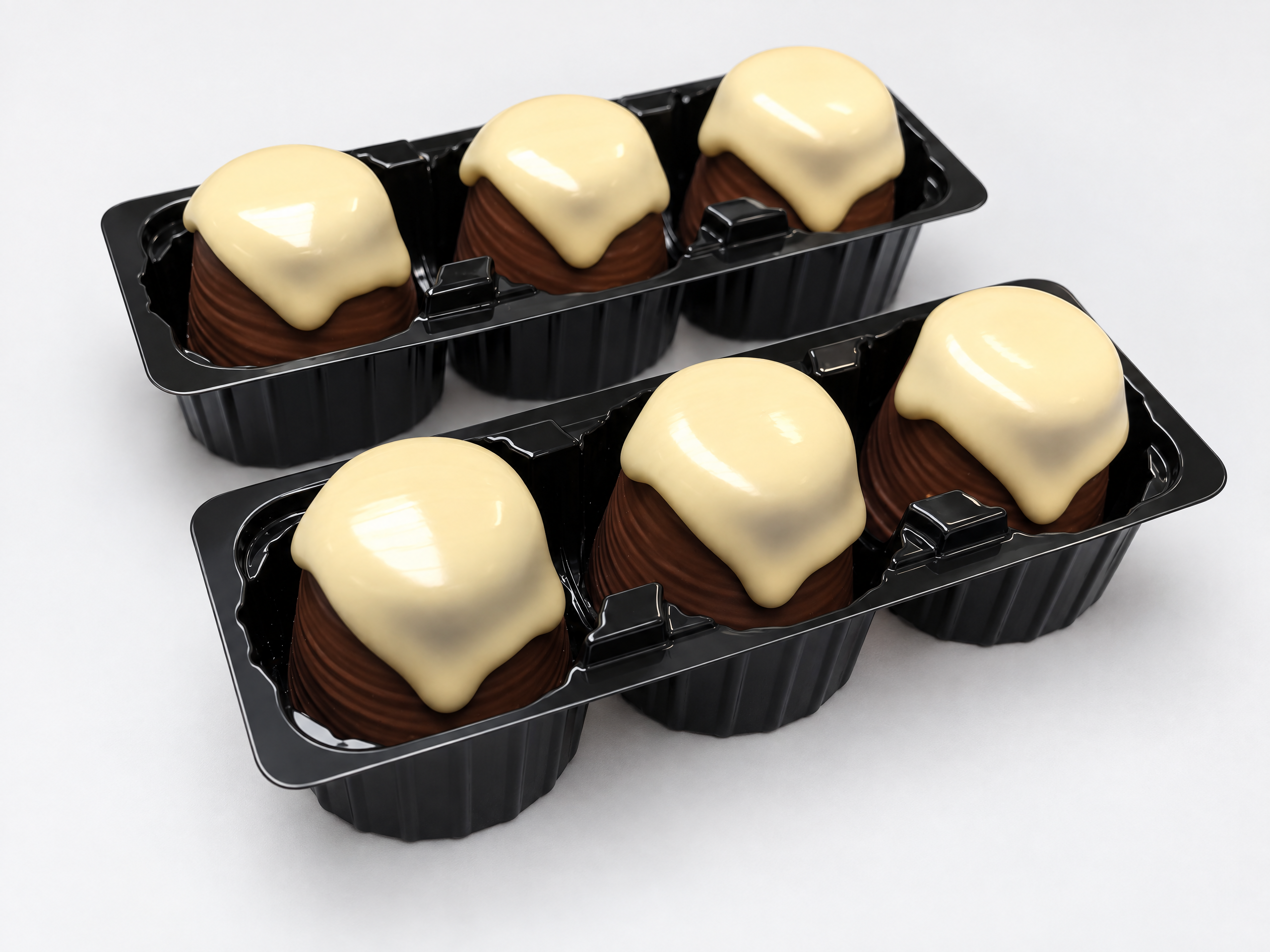 Mellow cakes with a white chocolate topping in black blister trays