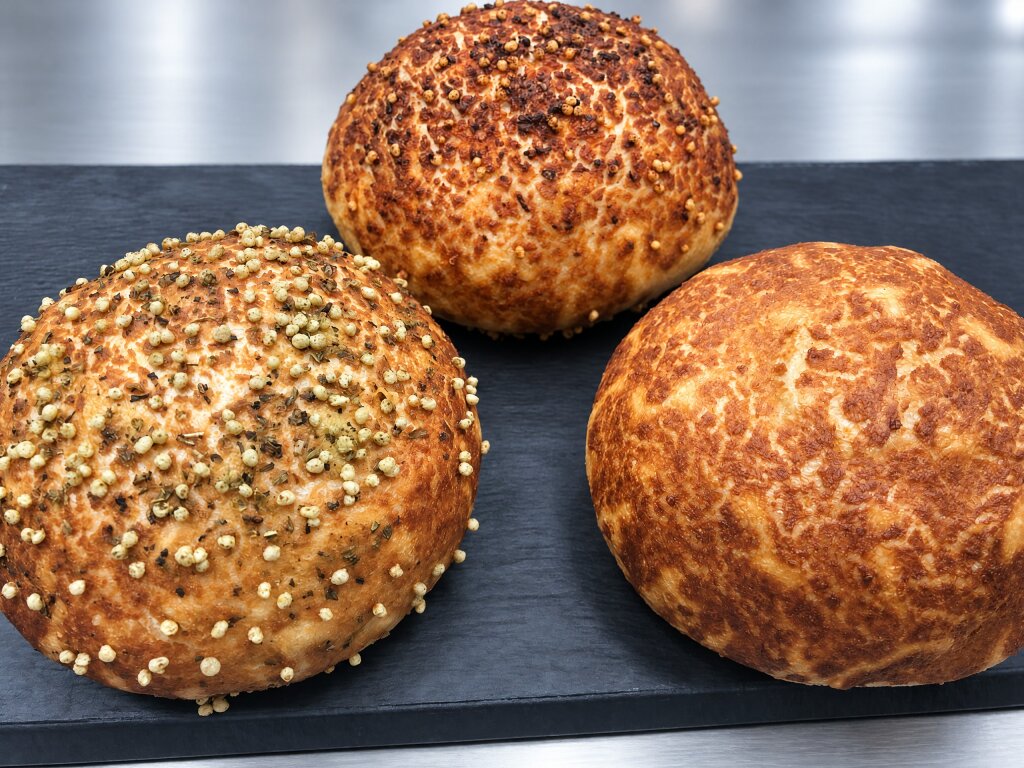 Three burger buns with tiger topping: herbs with puffed grains, paprika and plain